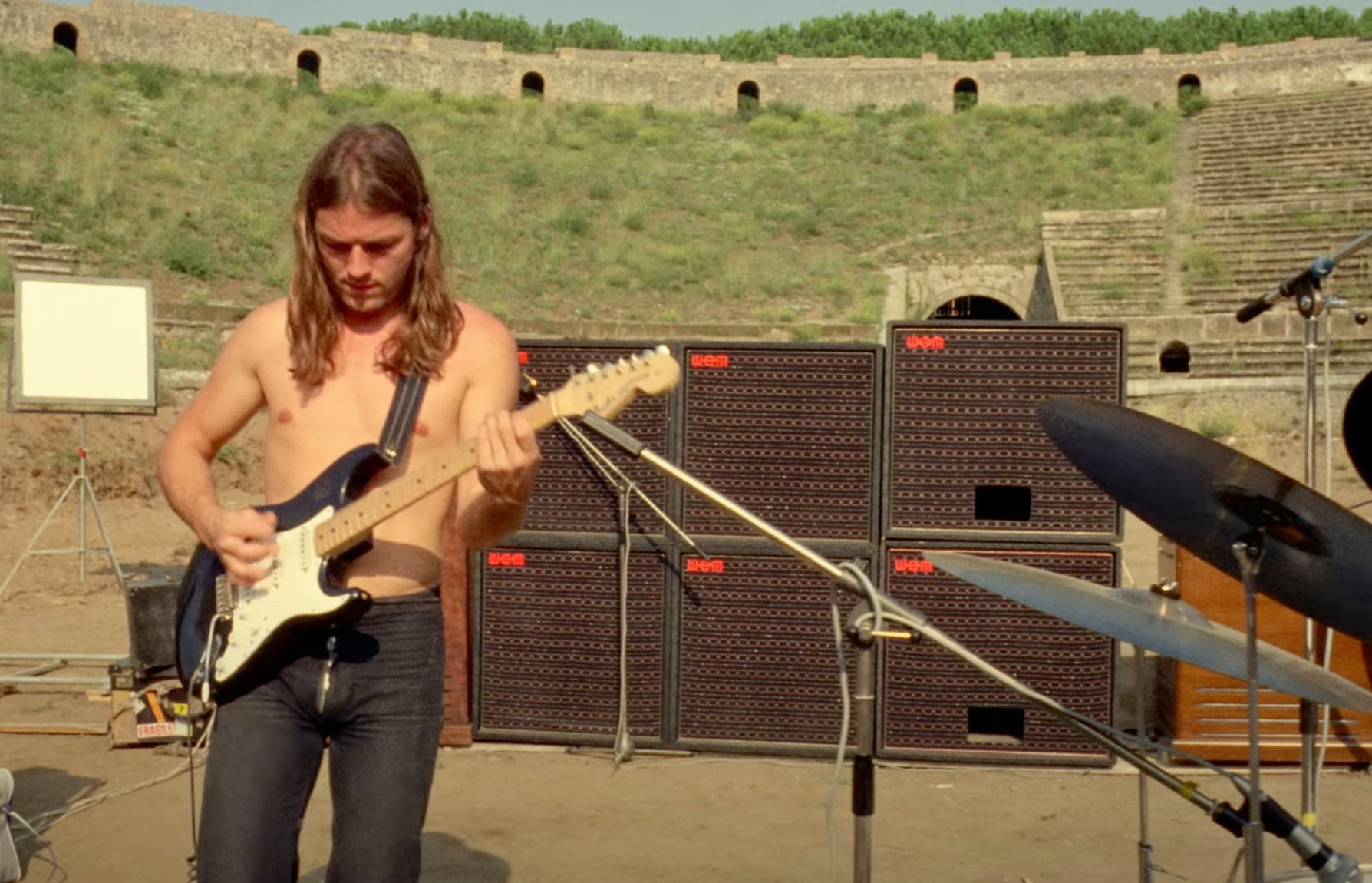 Gitarrist spielt E-Gitarre vor einer Reihe von Lautsprechern in einem Amphitheater.