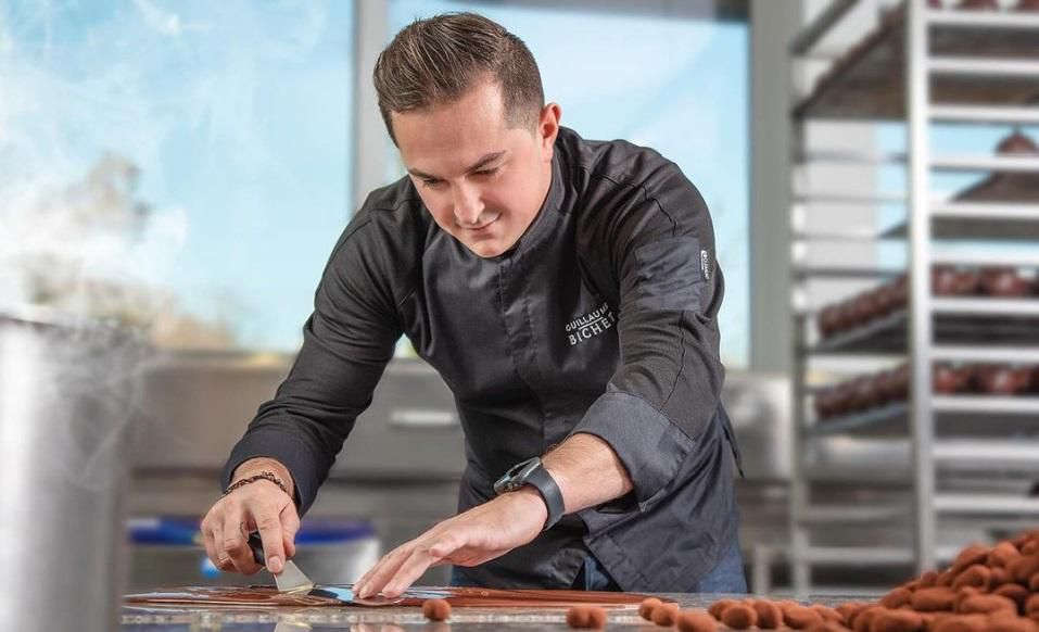 Chef pâtissier concentré préparant des desserts dans une cuisine professionnelle.