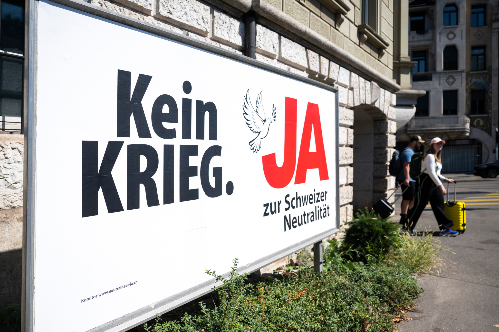 Plakat der Neutralitäts-Initiative mit der Aufschrift «Kein Krieg. JA zur Schweizer Neutralität» und einer Friedenstaube, aufgestellt an einer Stadtstrasse.