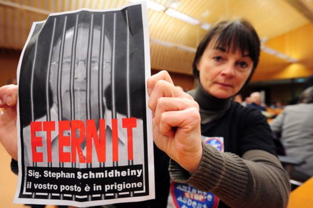 Une femme brandit lundi devant la cour de justice de Turin un portrait de Stephan Schmidheiny disant: «Ta place est en prison.»