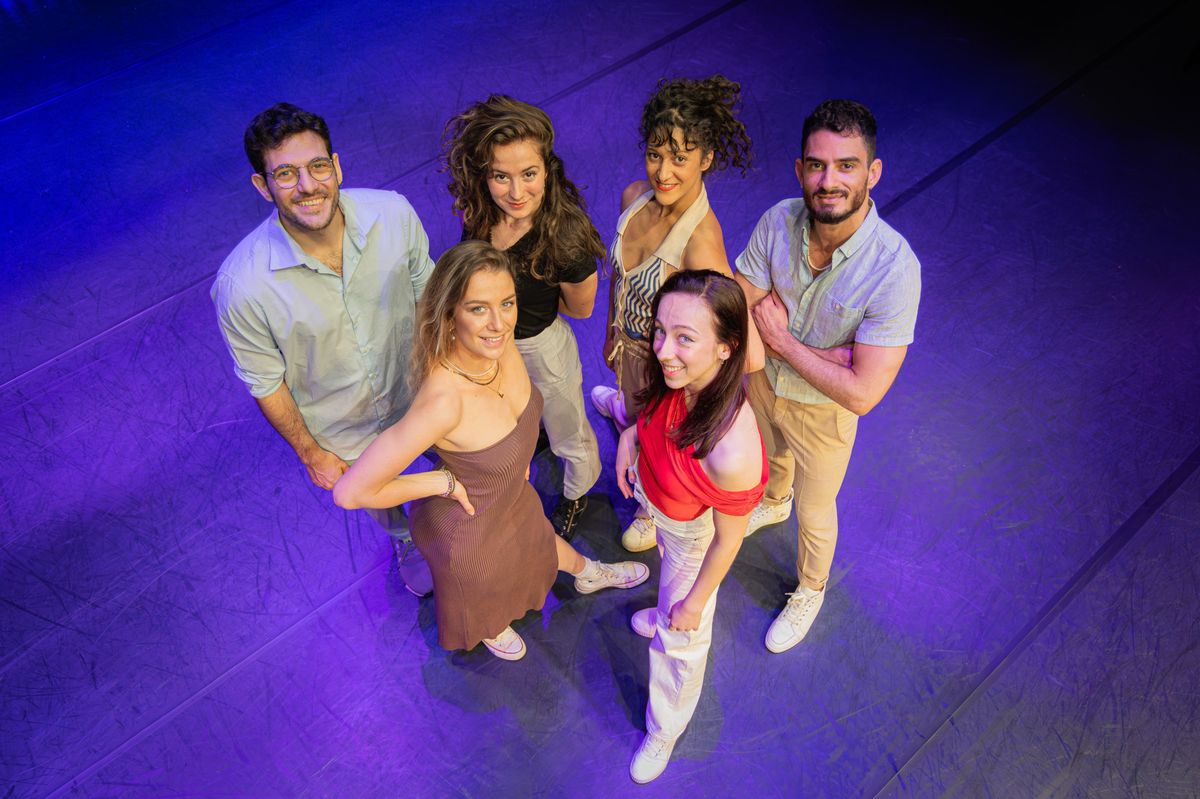 Six personnes posent ensemble sur une scène éclairée en violet, souriant pour la caméra.