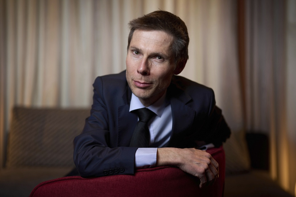 Lionel Baier pose devant un rideau, vêtu d’un costume sombre, lors d’un portrait au festival du film Berlinale 2025.