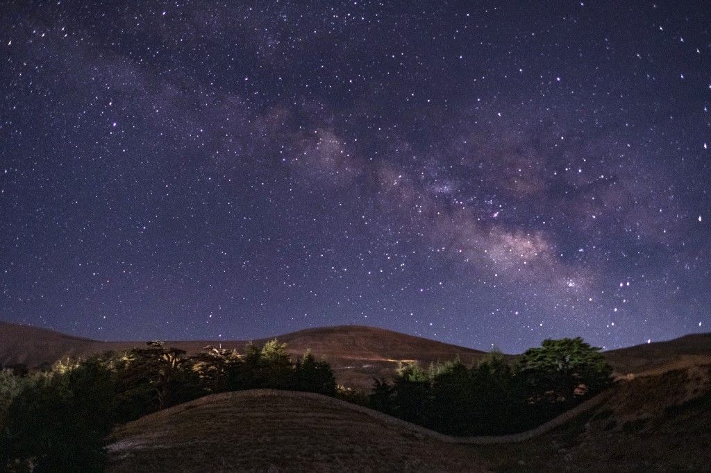 Stars and the milky way are seen in the sky above the Cedars forest known as the Cedars of God in the northern mountainous town of Bsharri at about 1900m above the sea level, some 117Km north of Lebanese capital Beirut, on July 10, 2021. (Photo by Ibrahim CHALHOUB / AFP)