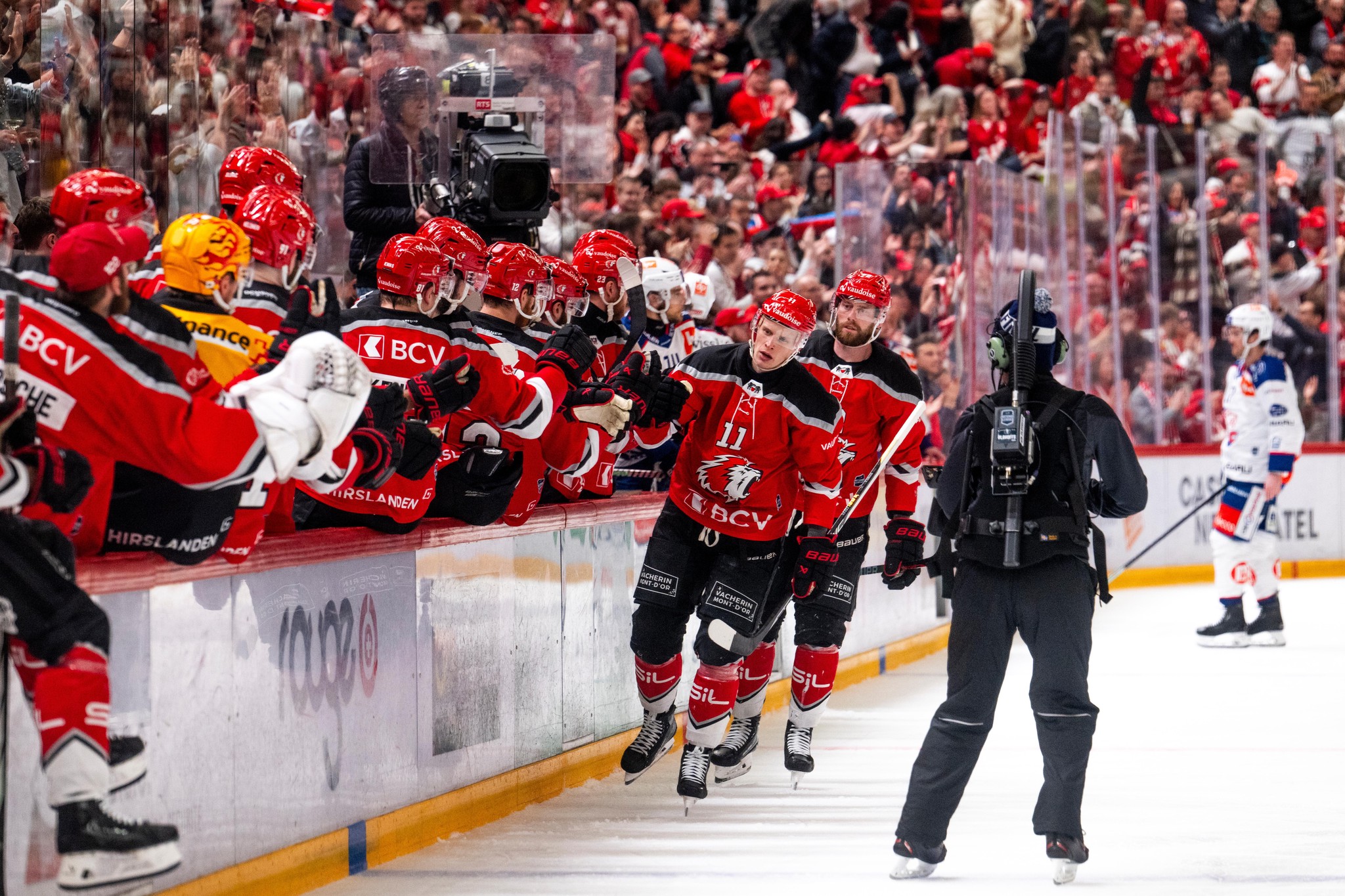 Antti Suomela und Lawrence Pilut von Lausanne HC jubeln nach dem 1:0 gegen die ZSC Lions im Eishockey-Playoff-Finale, Kameraaufzeichnung im Hintergrund.