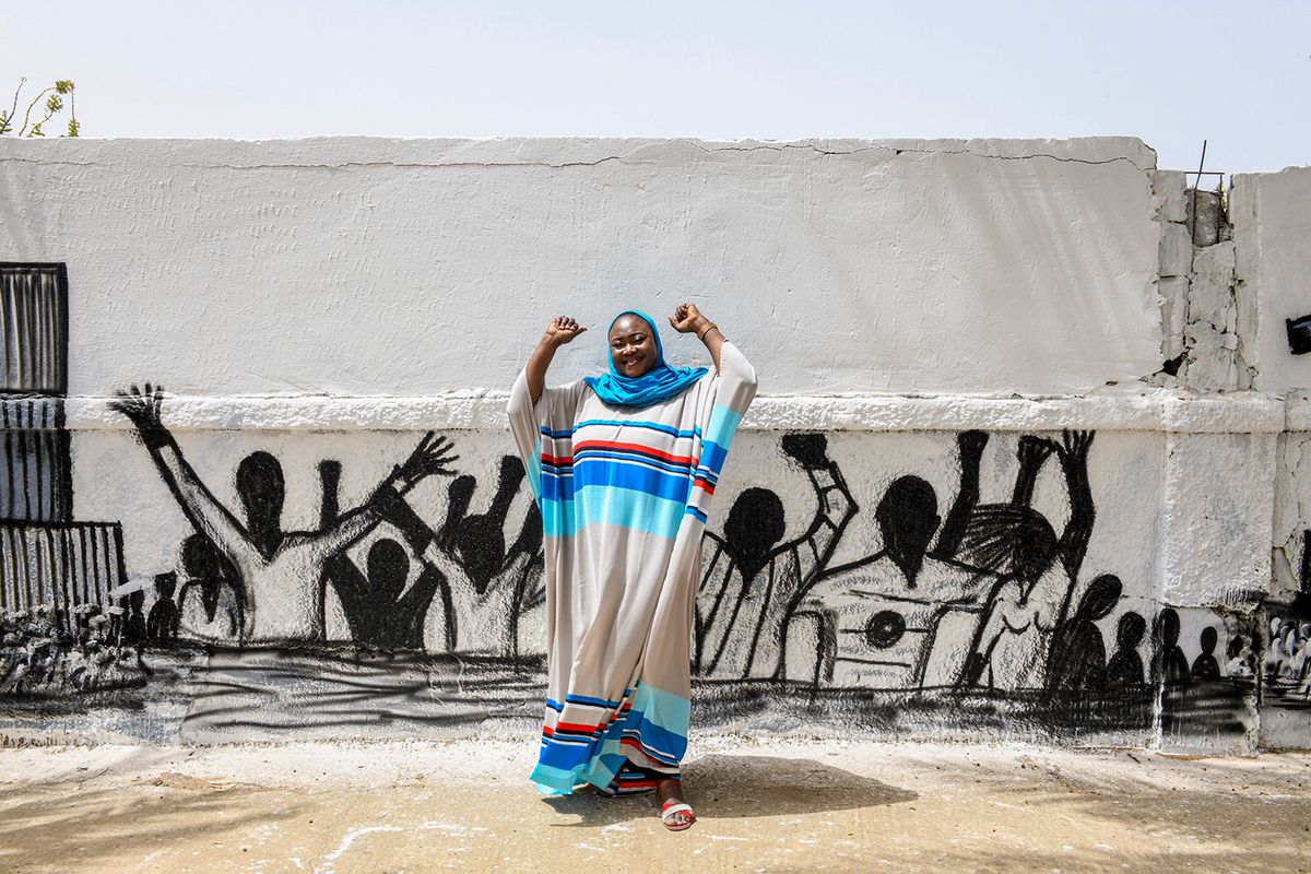 Une Sénégalaise pose devant un mur peint de Dakar.
