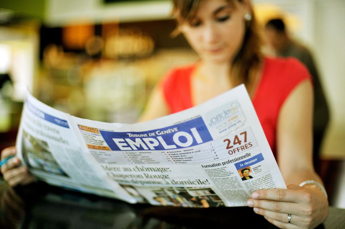 Femme lisant la section Emploi du journal Tribune de Genève avec un titre sur le chômage.