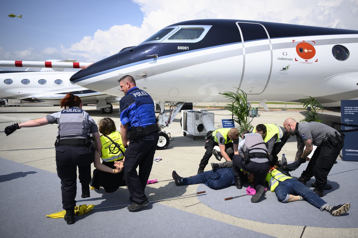 Des policiers arrêtent des activistes environnementaux de Stay Grounded, Greenpeace, Extinction Rebellion et Scientist Rebellion menottés à un avion lors de la convention EBACE à l'aéroport de Genève, Suisse, le 23 mai 2023.