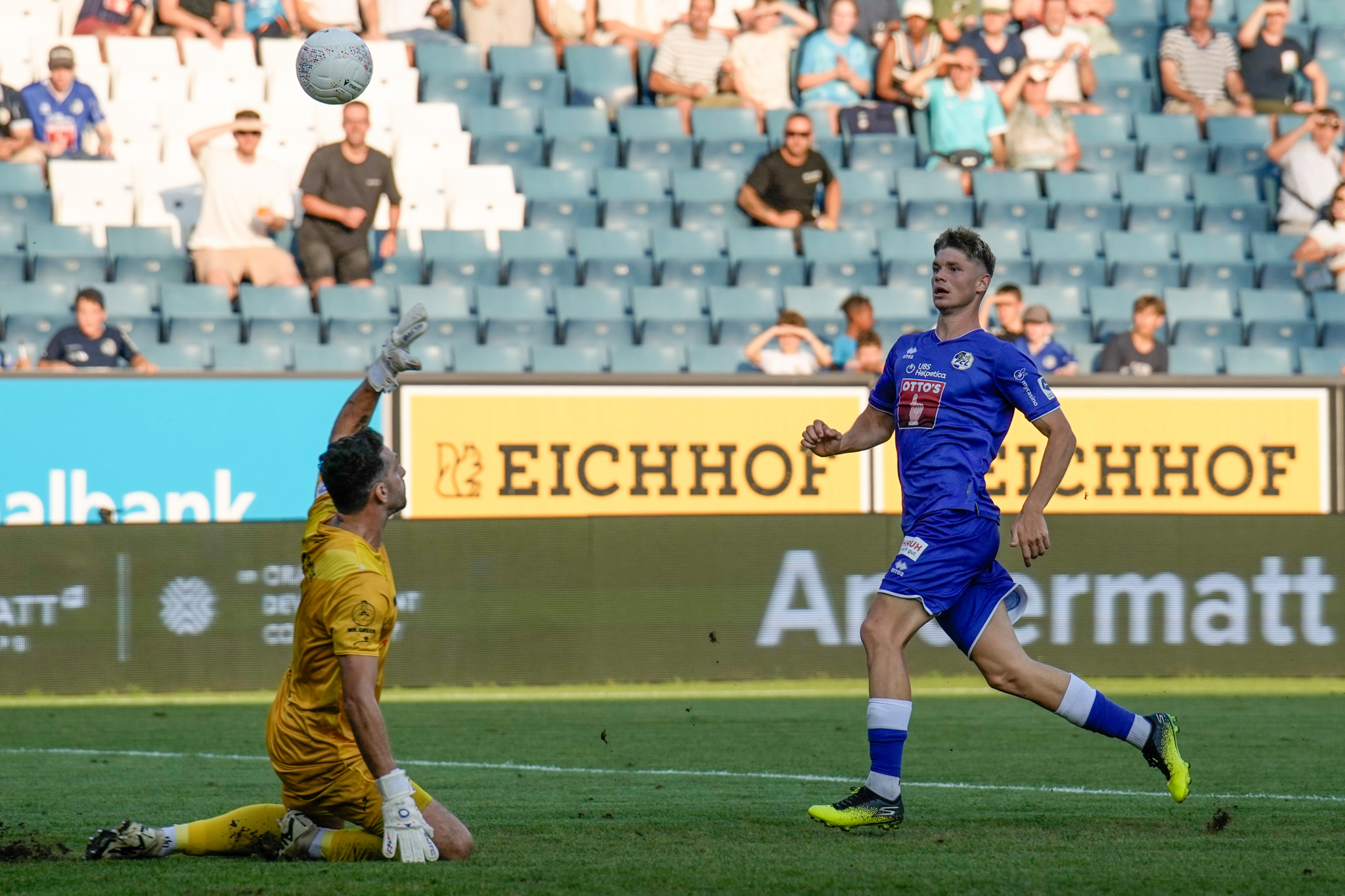 Lars Villiger vom FC Luzern erzielt ein Tor gegen Torhüter Stefanos Kapino vom FC Winterthur während eines Super League-Spiels in Luzern. Zuschauer im Hintergrund.