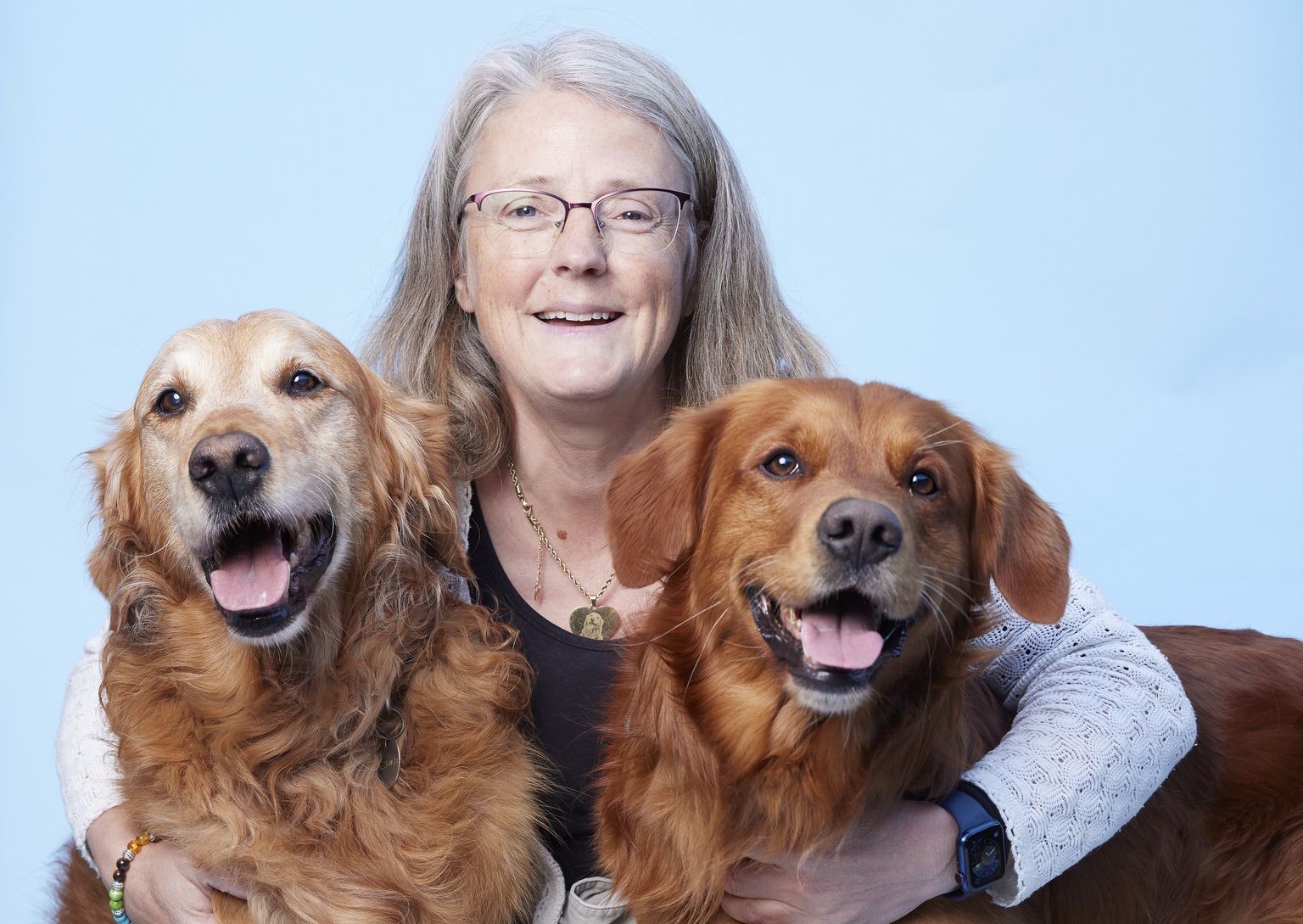 Karine est comblée auprès de ses deux chiens sauveteurs, Sunbeam, le plus clair des deux, à gauche et Arrow, le plus jeune, à droite. Pour l’aider à affronter la maladie de Sunbeam, Karine a reçu un collier avec son portrait gravé.