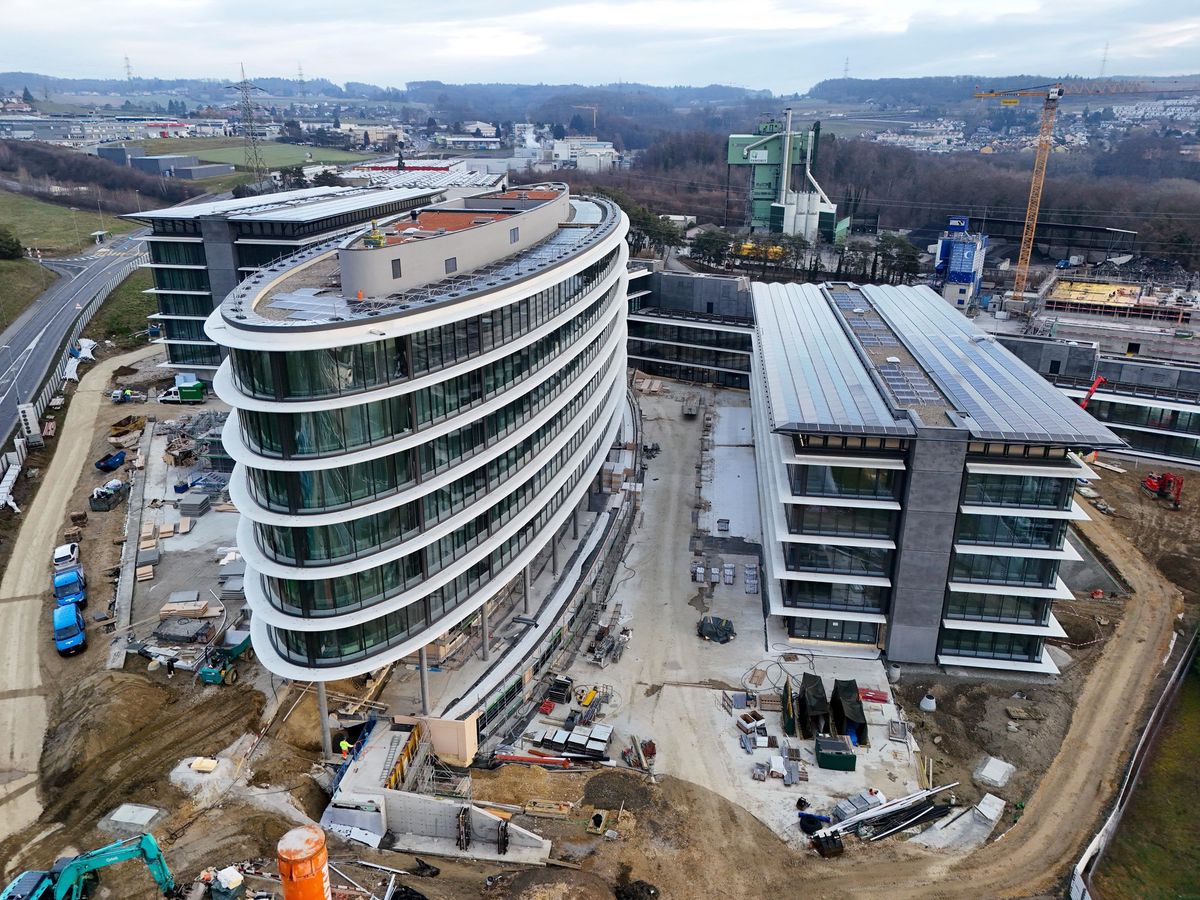 Vue aérienne d’un chantier à Bussigny avec plusieurs immeubles de bureaux en construction, illustrant le besoin de surfaces d’activité dans l’agglo Lausanne-Morges. Grues et équipements de construction visibles sur le site.