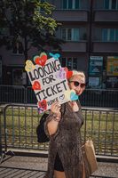 Does that still work? A woman is looking for a ticket to a concert with an elaborately designed poster.