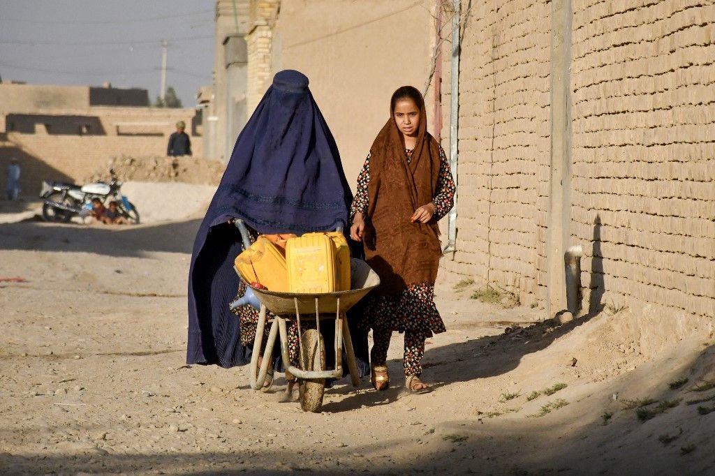 Une femme afghane en burqa pousse une brouette près de Mazar-i-Sharif, accompagnée d'une jeune fille, le 25 septembre 2024.