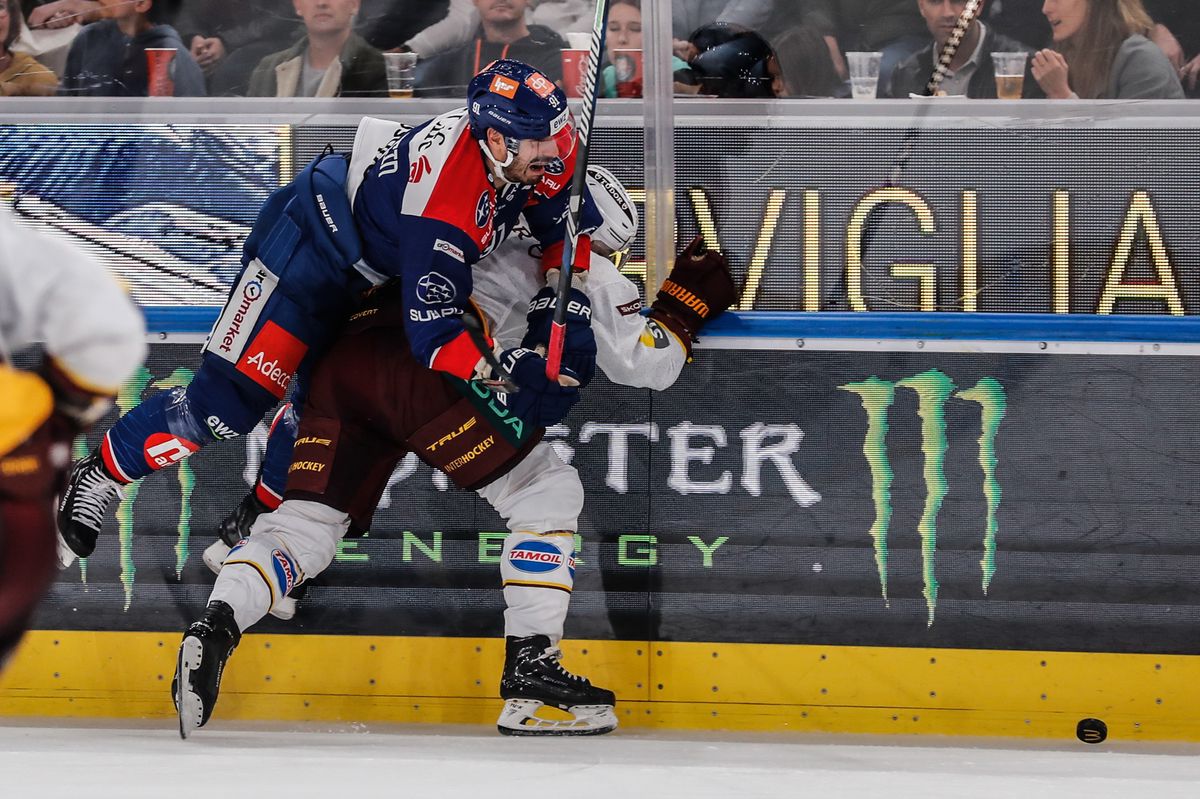 ZSC Denis Hollenstein, links, kaempft um den Puck gegen Servettes Roger Karrer, rechts, im Eishockeyspiel der National League zwischen den ZSC Lions und Geneve-Servette HC am Sonntag, 22. Oktober 2023, in der Swiss Life Arena in Zuerich. (KEYSTONE/Siggi Bucher)