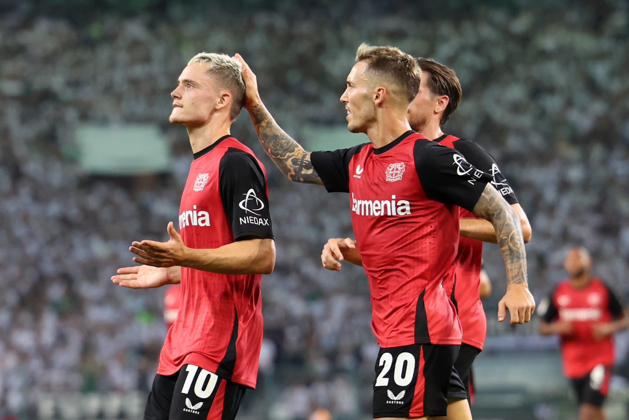 Florian Wirtz von Leverkusen feiert nach dem Tor zum 2:0 gegen Borussia Mönchengladbach im Bundesliga-Spiel am 23. August 2024. Neben ihm steht ein Mitspieler und legt ihm die Hand auf den Kopf.