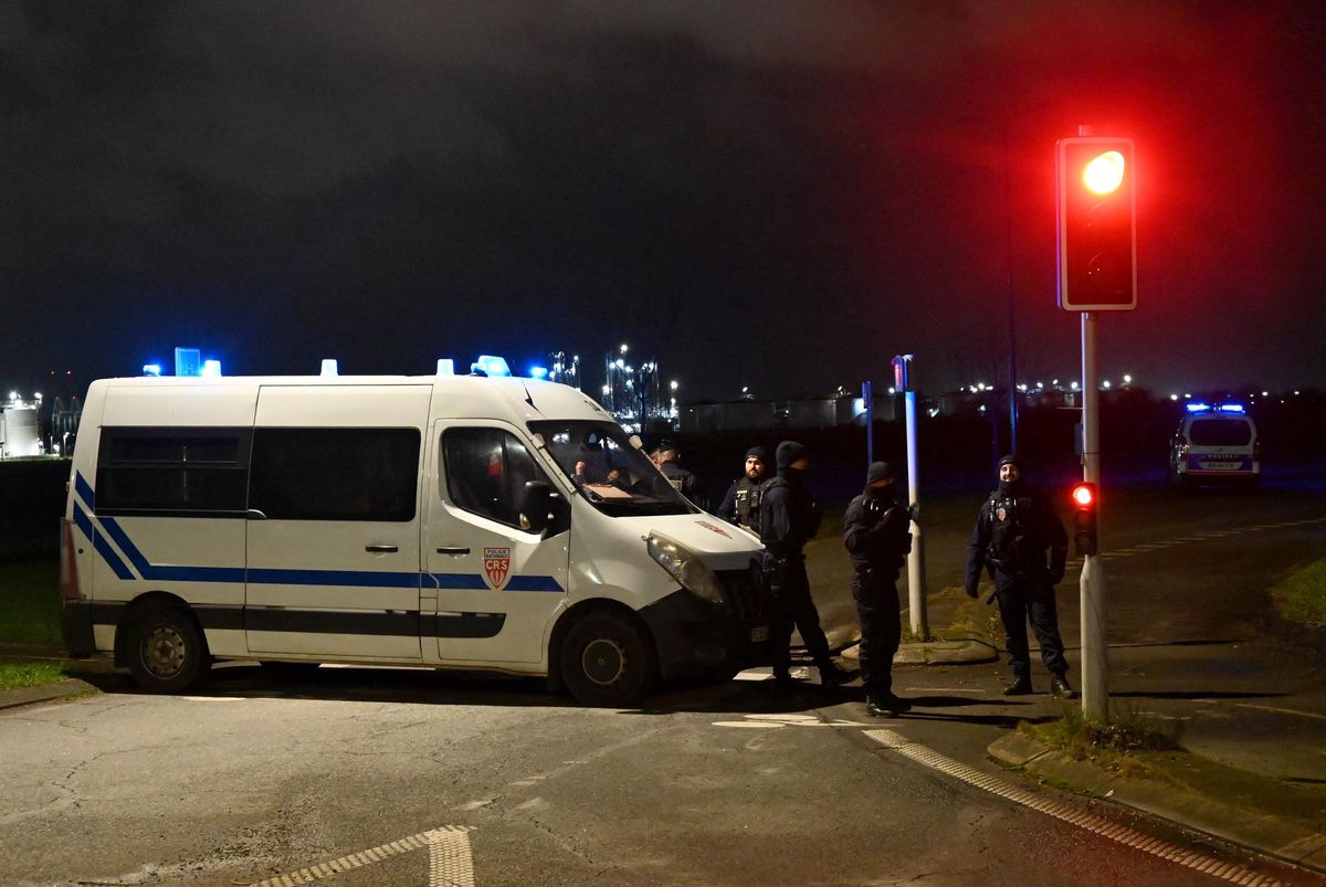 CRS françaises bloquant une route près d’un camp de migrants à Dunkerque, après que cinq personnes ont été tuées, y compris deux agents de sécurité et deux migrants, le 14 décembre 2024. Photo de nuit avec camionnette de police et agents sécurisant la zone.