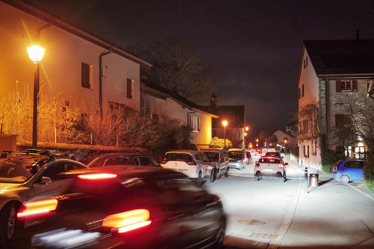 Rue de Soral à Genève tôt le matin, avec des maisons et des voitures éclairées par des lampadaires.