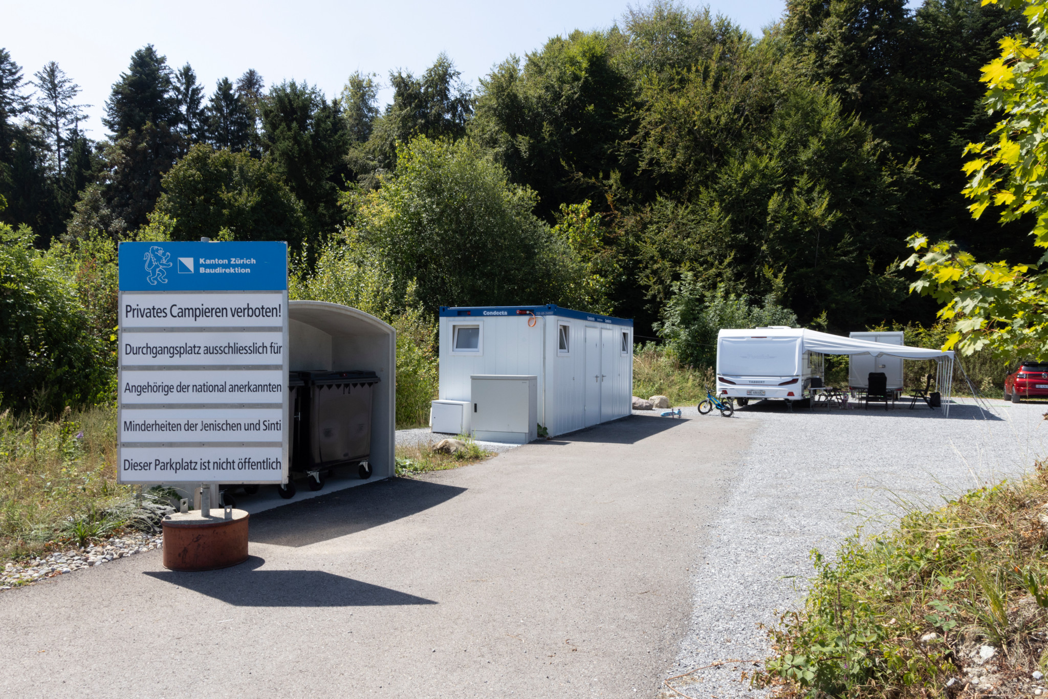 Durchgangsplatz Gerenau in Wädenswil nach Sanierung wiedereröffnet: Schild mit Hinweis «Privates Campieren verboten», Sanitärcontainer und Wohnwagen auf dem Platz.