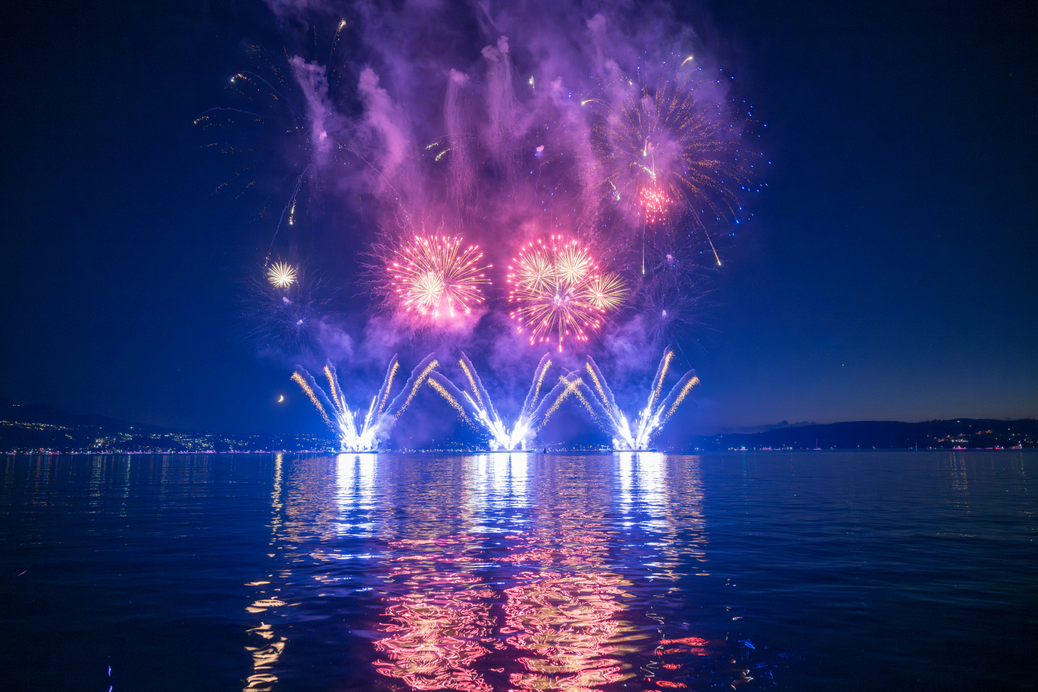 Farbenfrohes Feuerwerk beim Seenachtsfest Rapperswil 2024, mit violetten und rosa Lichtern, die sich im See spiegeln.
