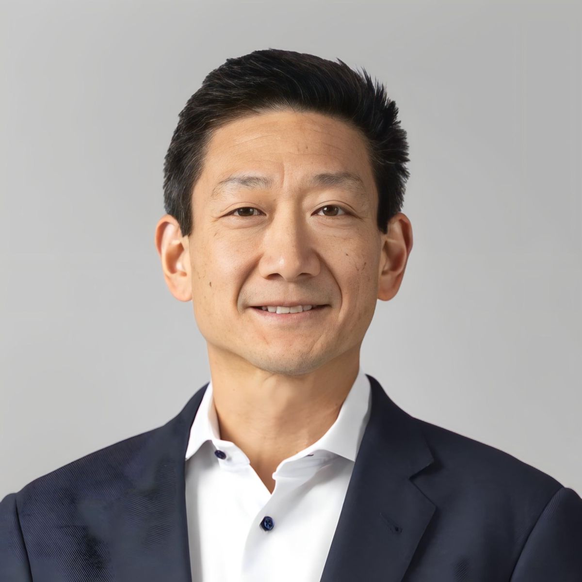 Porträt Nelson Yu in einem Anzug mit hellem Hintergrund.