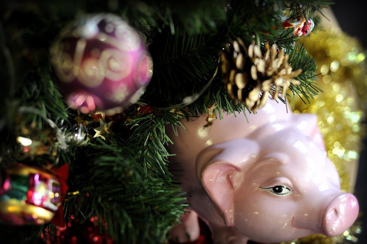Décorations de Noël avec un cochon en céramique rose et boules colorées sur un sapin à Genève.