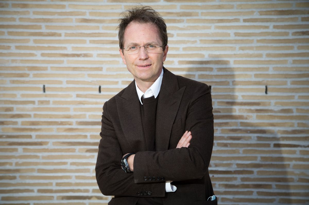 Jean Liermier, directeur du Théâtre de Carouge, pose avec les bras croisés devant un mur en briques.