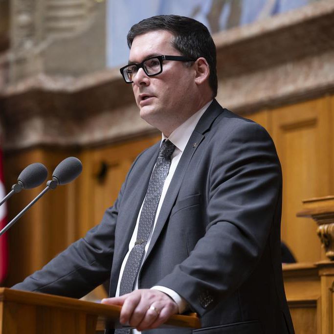 David Zuberbuehler, membre de l’UDC-AR, s’exprime lors de la session d’hiver au Conseil national à Berne, avec un drapeau suisse en arrière-plan.