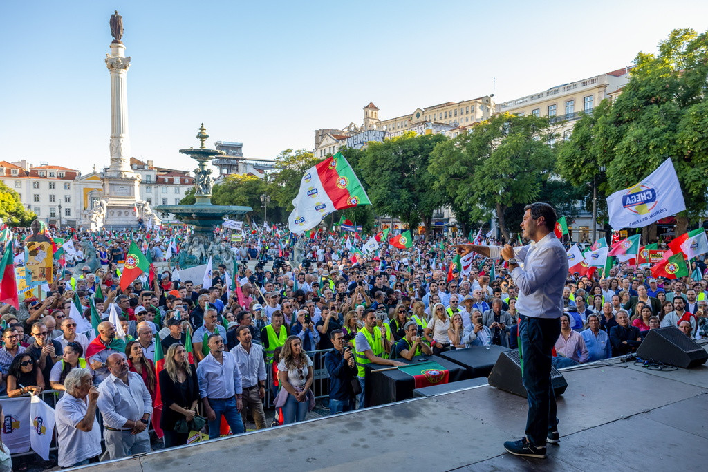 André Ventura, leader du parti d'extrême droite Chega, prononce un discours lors d'une manifestation à Lisbonne contre l'immigration incontrôlée et l'insécurité, avec de nombreux manifestants portant des drapeaux.