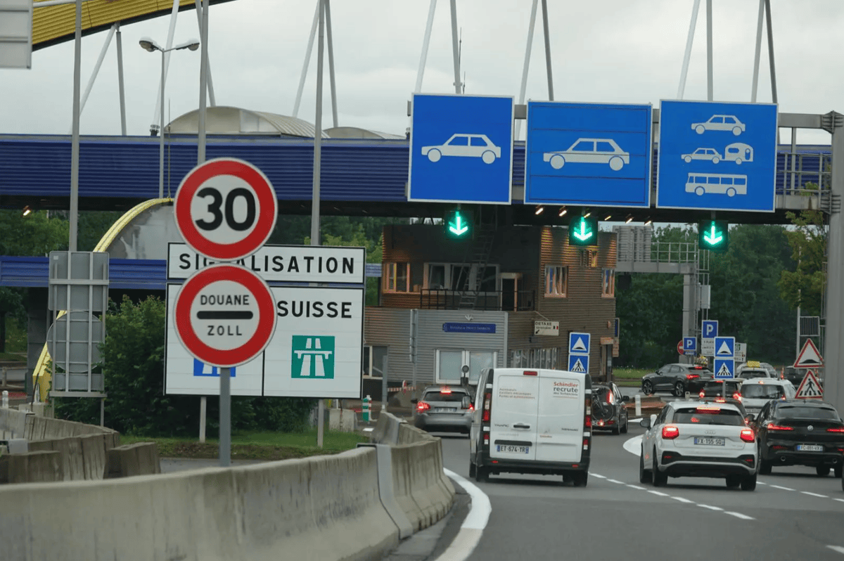 Poste frontière suisse avec panneaux de signalisation et trafic routier.