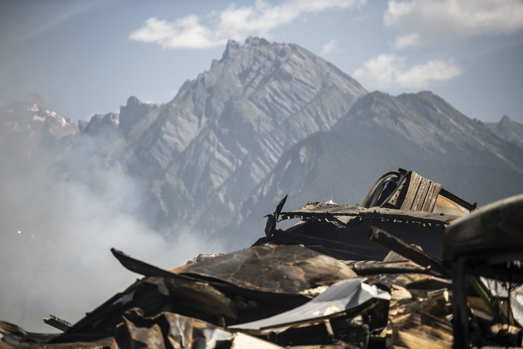 Décombres calcinés d'une halle industrielle à Vetroz, avec une montagne en arrière-plan. Incendie maîtrisé après avoir mobilisé 140 pompiers sans faire de blessés.