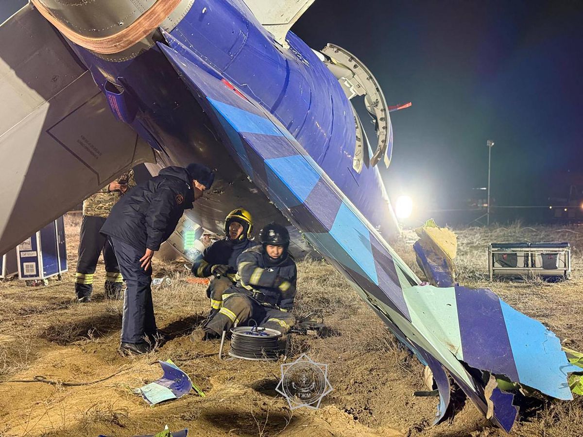 Des spécialistes de l’urgence inspectent le site du crash d’un avion d’Azerbaijan Airlines près d’Aktau, Kazakhstan, avec des débris visibles.