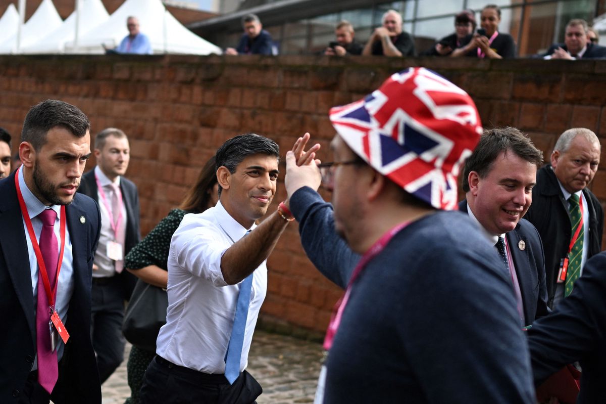 Britain's Prime Minister Rishi Sunak (L) shakes hands with a supporter as he walks through the venue on the first day of the annual Conservative Party Conference in Manchester, northern England, on October 1, 2023. (Photo by Oli SCARFF / AFP)