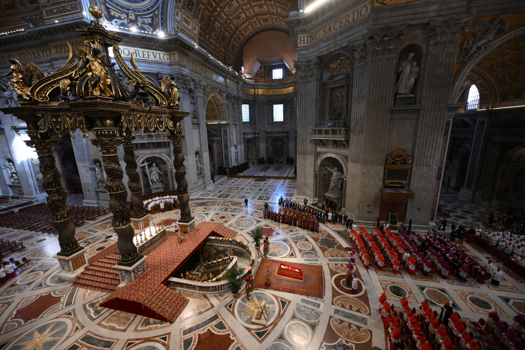 Kardinal Camerlengo Kevin Joseph Farrell betet im Petersdom vor dem Leichnam von Papst Franziskus, flankiert von Monsignore Krzysztof Marcjanowicz und Erzbischof Diego Giovanni Ravelli, 23. April 2025.
