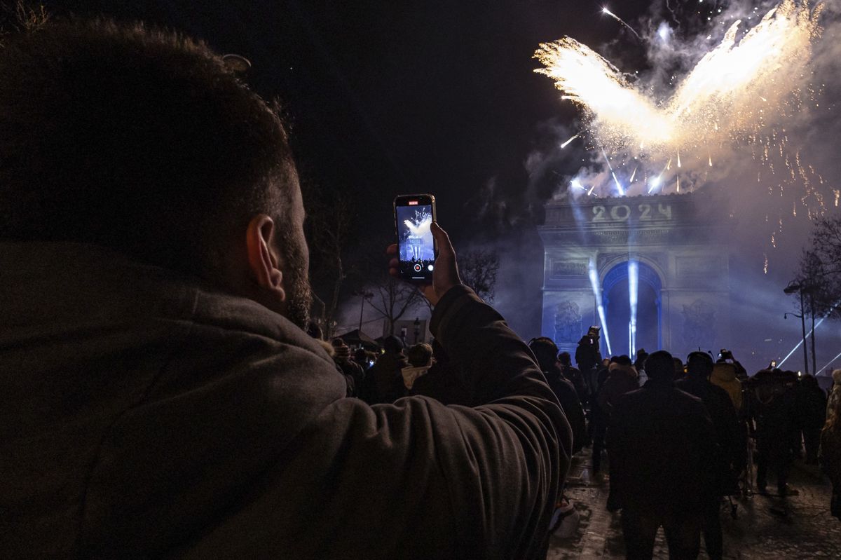 Revelers watch a light show projected on the Arc de Triomphe as they celebrate the New Year on the Champs Elysees, in Paris, France, Monday, Jan. 1, 2024. (AP Photo/Aurelien Morissard)