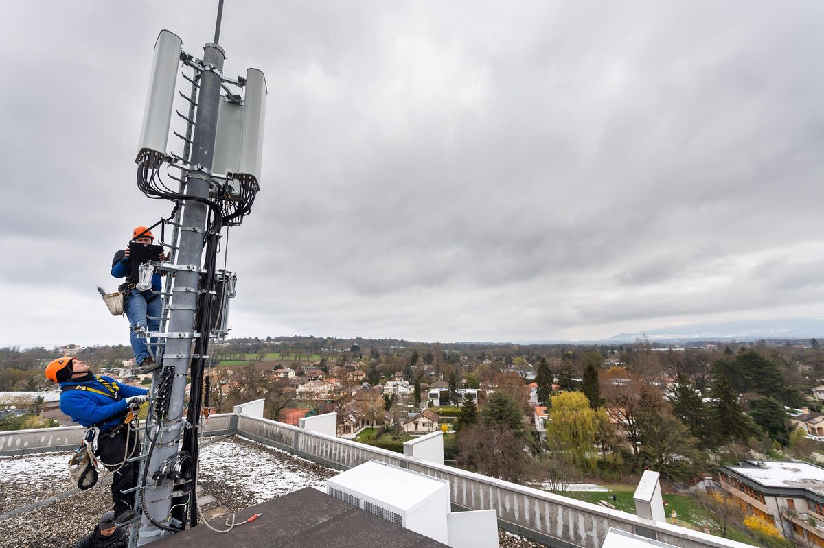 Deux techniciens installent une antenne 5G sur un mât situe sur le toit d’un immeuble de Chêne-Bougeries (GE), le 5 avril 2019. La 5G millimétrique, qui permet une puissance nettement supérieure à la 4G, n’est cependant pas encore utilisée en Suisse.