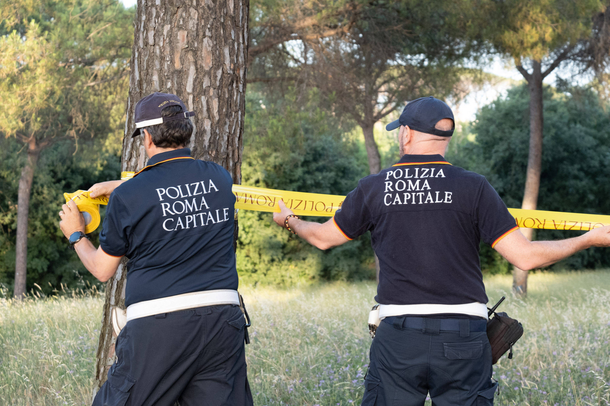 Zwei Polizisten sperren ein Gebiet in der Villa Doria Pamphilj in Rom mit gelbem Band ab.