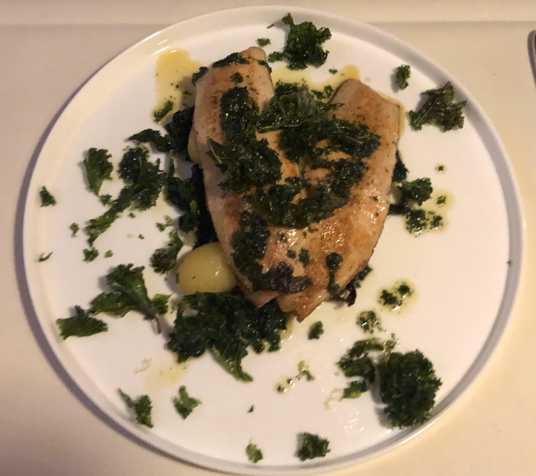 Gebratener Fischfilet auf Kartoffeln, garniert mit Kräutersosse.