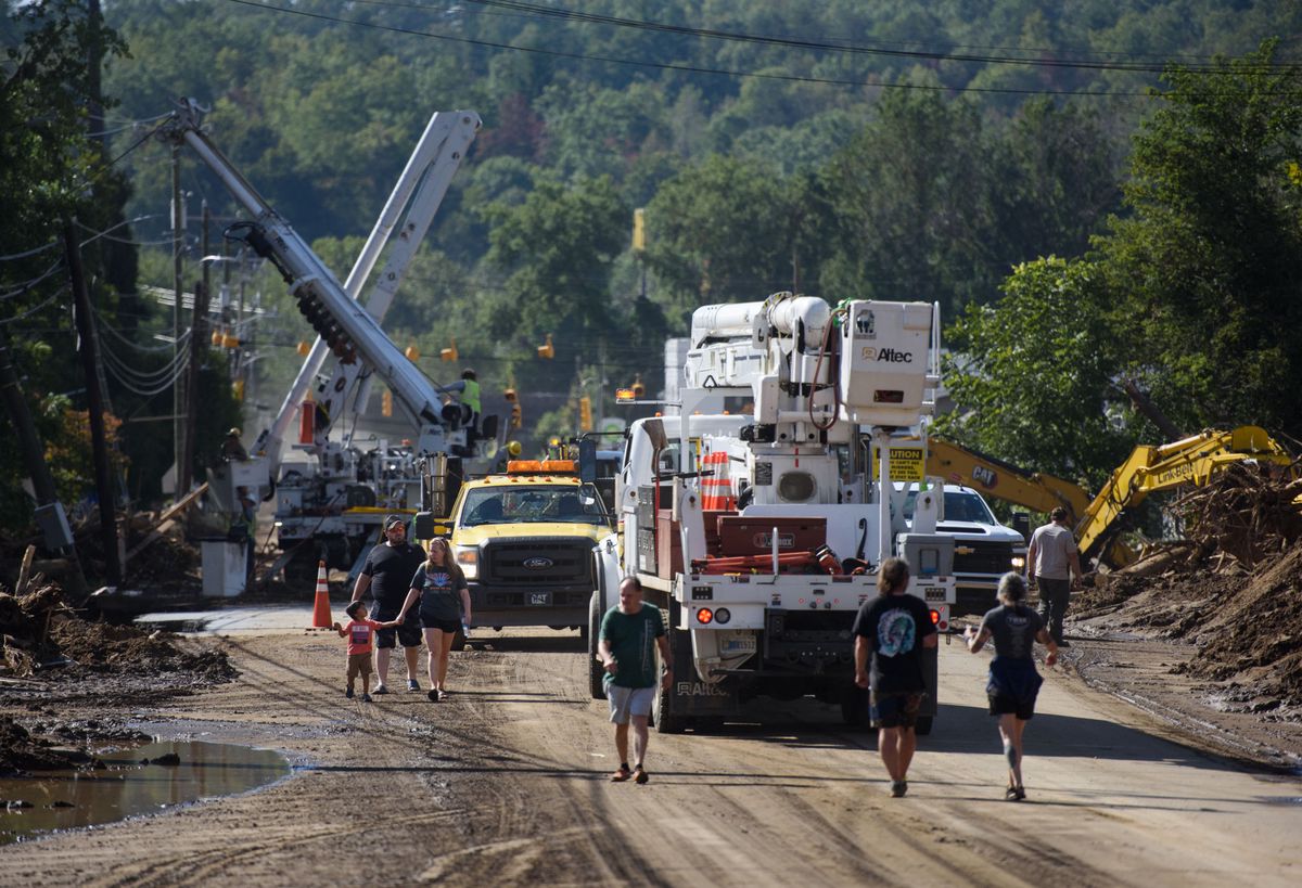 Des personnes inspectent les dégâts tandis que des travailleurs déblayent les débris d'un pont sur l'avenue Catawba à Old Fort en Caroline du Nord, à la suite de l'ouragan Hélène.