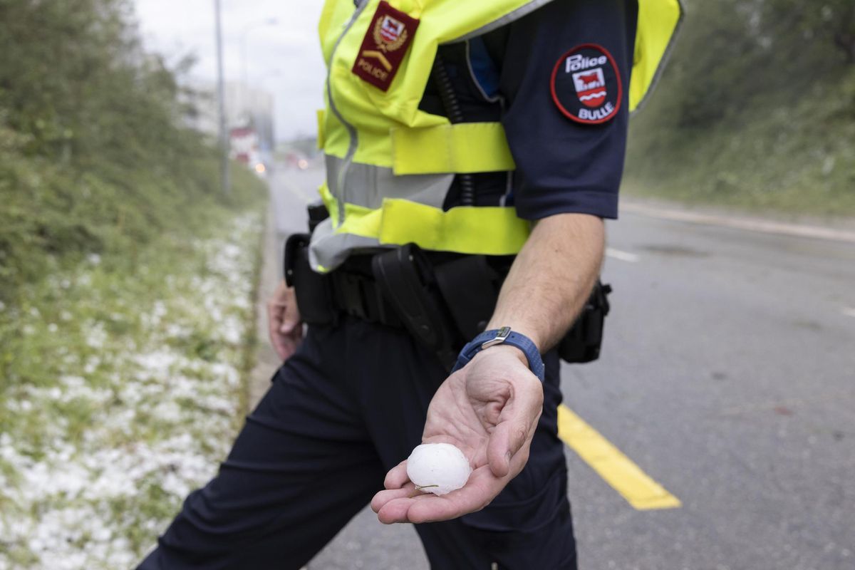 Un agent de police tien un grêlon après le violent orage de grêle à Bulle. 