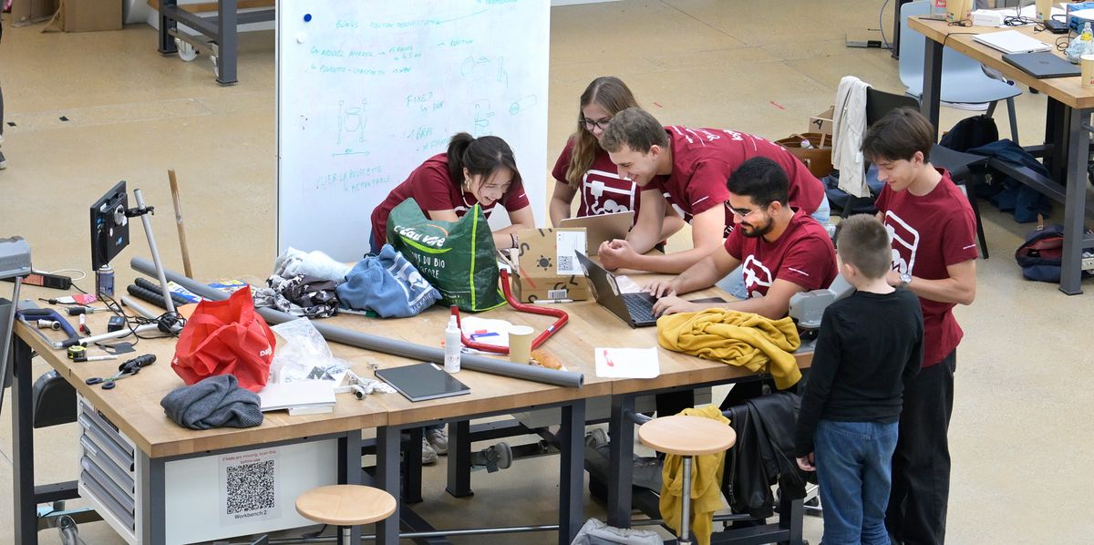 Participants du hackathon organisé par l'association hackaHealth à l'EPFL à Lausanne le 27 septembre 2024, travaillant ensemble autour d'une table remplie de matériel et d'équipements divers. 
