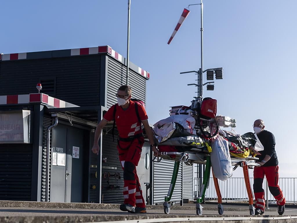 Un équipage Rega s’apprête à charger un patient Covid dans un hélicoptère de la Rega en vue de son transfert à l'Hôpital de l'Ile à Berne. Un équipage Rega s’apprête à charger un patient Covid dans un hélicoptère de la Rega en vue de son transfert à l'Hôpital de l'Ile à Berne.