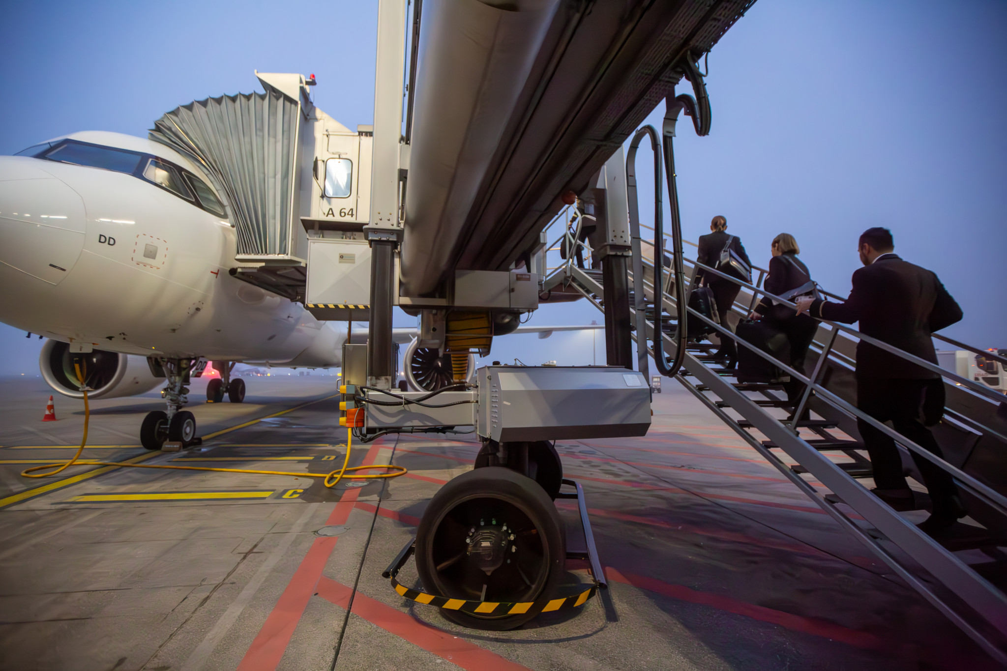 Passagiere betreten ein Flugzeug über eine mobile Treppe am Flughafen.