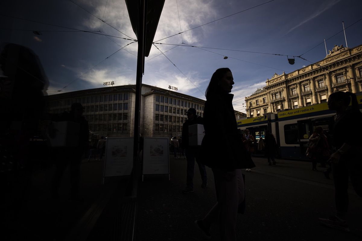 People walk past the headquarters of Swiss bank Credit Suisse, right, and UBS, left, at Paradeplatz in in Zurich, Switzerland on Saturday, March 18, 2023. (KEYSTONE/Michael Buholzer).