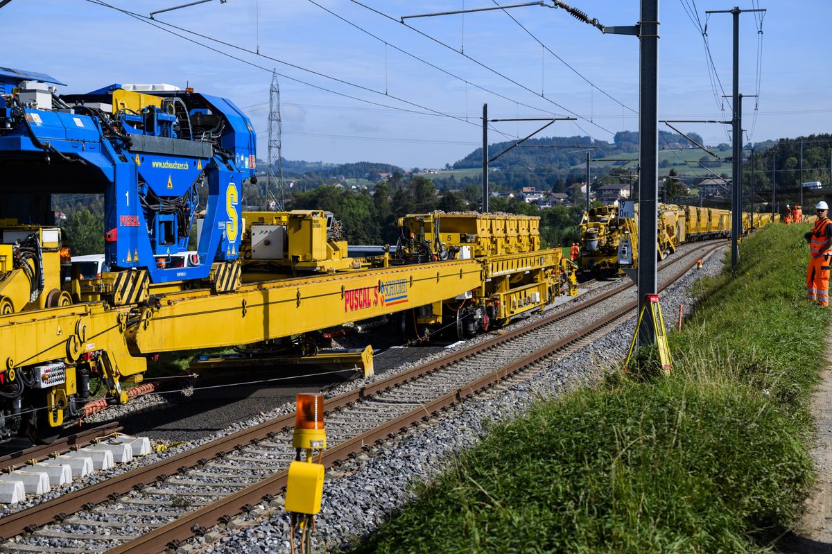 Des ouvriers travaillent a cote de la machine "Puscal" de l'entreprise Scheuchzer lors d'une visite de presse sur le chantier d'entretien des voies CFF de 7km de long entre Puidoux et Palezieux le jeudi 5 octobre 2023 pres de la gare de Palezieux. (KEYSTONE/Jean-Christophe Bott)