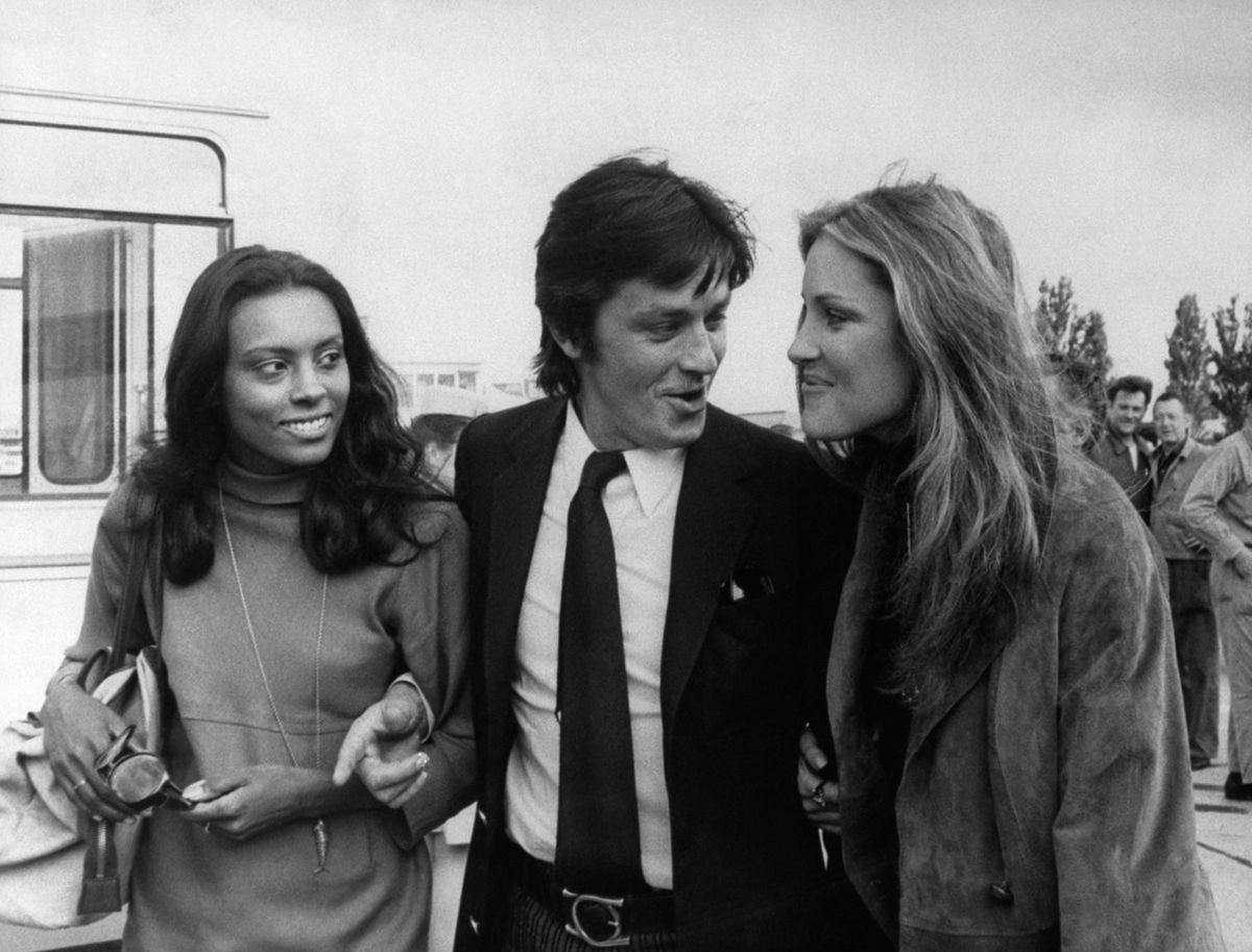 FILE - French actor Alain Delon is escorted by American actresses Jane Davenport, left, and Pamela Huntington after their arrival from New York at Orly airport in Paris on Aug.19, 1970. Alain Delon, the internationally acclaimed French actor who embodied both the bad guy and the policeman and made hearts throb around the world, has died at age 88, French media reported. (AP Photo/Laurent Rebours, File)