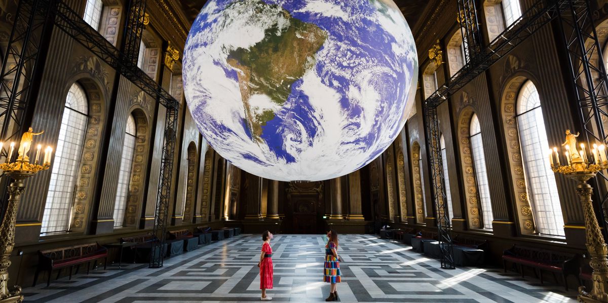 epa09240516 Members of staff pose with Luke Jerram's installation of a giant globe called 'Gaia' during a photocall at the Painted Hall in the Royal Naval College in Greenwich, London, Britain, 01 June 2021. The seven metre sculpture is an internally lit replica of the planet Earth using NASA imagery. It rotates and aims at replicating a sense of the 'Overview Effect' that astronauts experience when they see our home earth from space. EPA/VICKIE FLORES