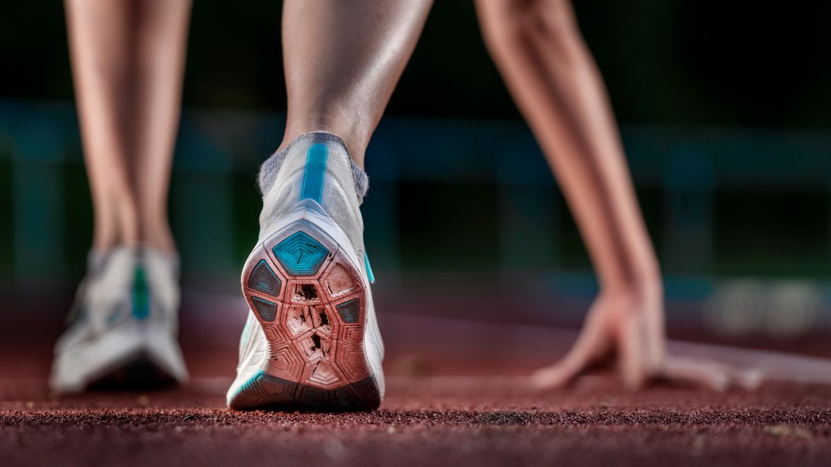 Legs of female athlete running on tartan track
