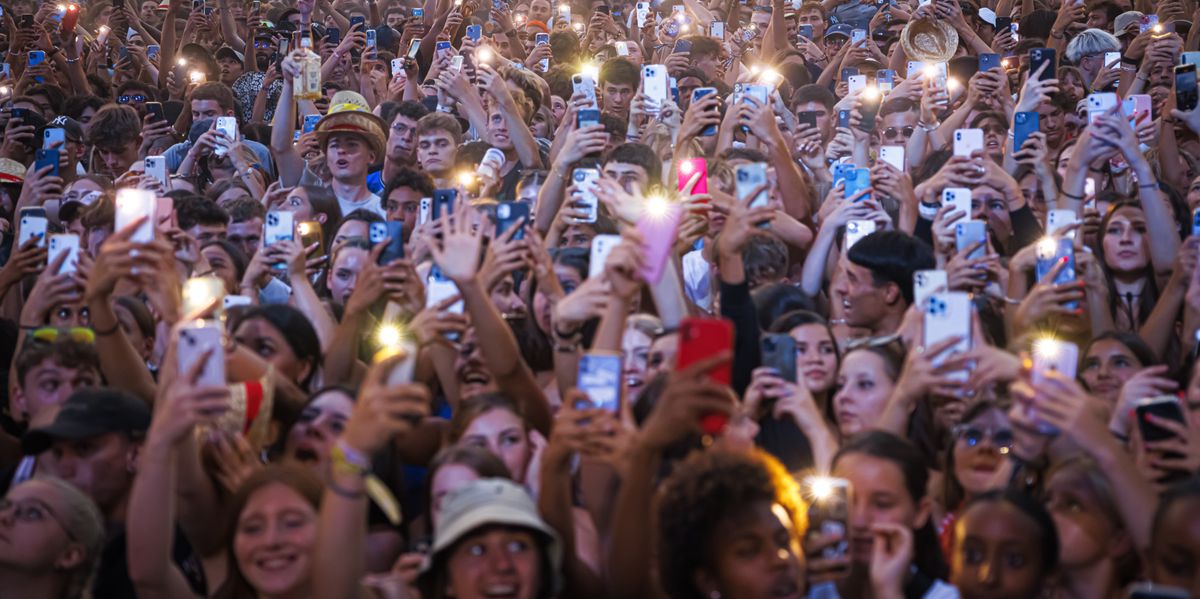Une foule dense avec des gens tenant des téléphones portables allumés lors d'un concert.