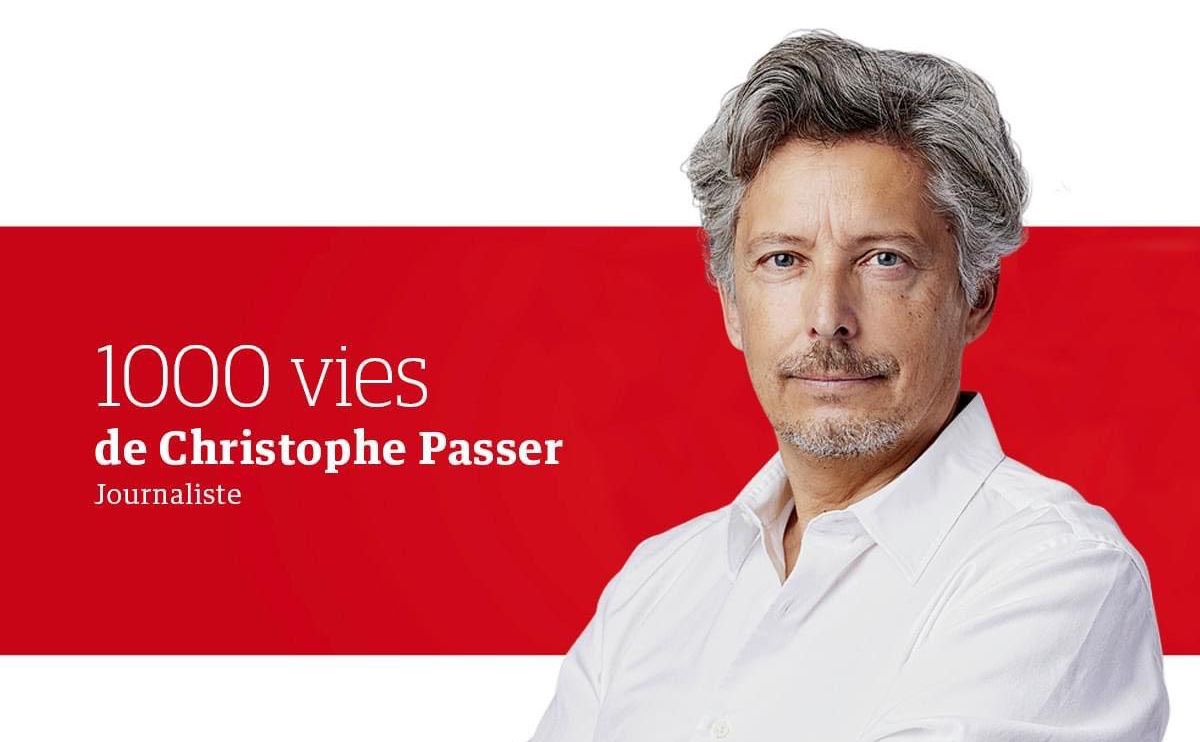 Un homme aux cheveux gris portant une chemise blanche se tient devant un fond rouge avec le texte ’1000 vies de Christophe Passer Journaliste’.