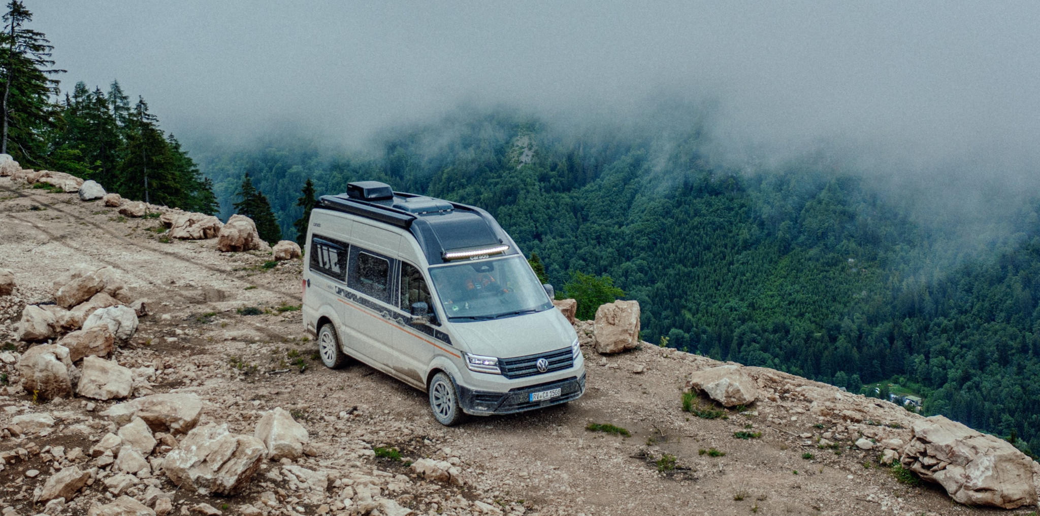 Carado CV 595 X-Edition Camper-Van mit Allradantrieb auf einem felsigen Berggipfel vor nebelverhangenen Wäldern