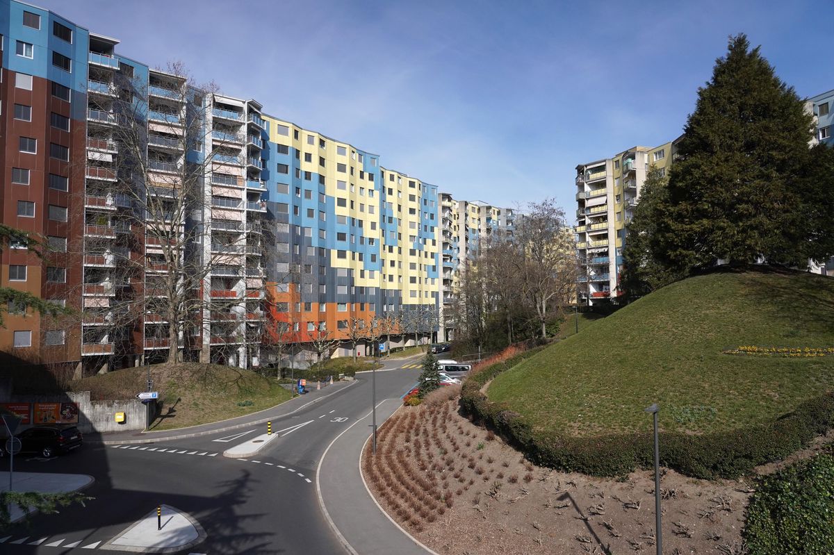 Immeubles résidentiels colorés dans le quartier des Avanchets à Genève, entourés de végétation et d’une route sinueuse.